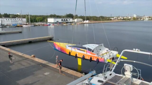 Guerrera being lowered into the marina, keel just touching the water, crew handling dock lines